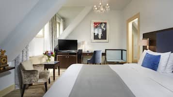 Una habitación de hotel con cama, escritorio, silla, televisor y candelabro.
