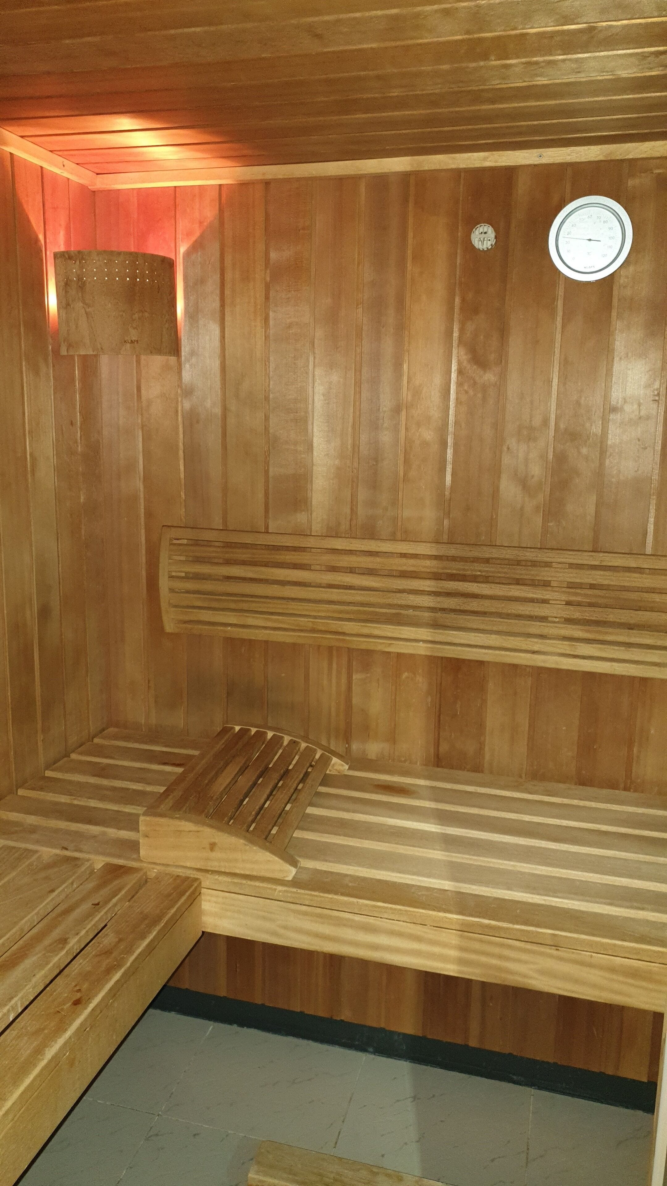 Una sauna con bancos de madera y un termómetro en la pared.