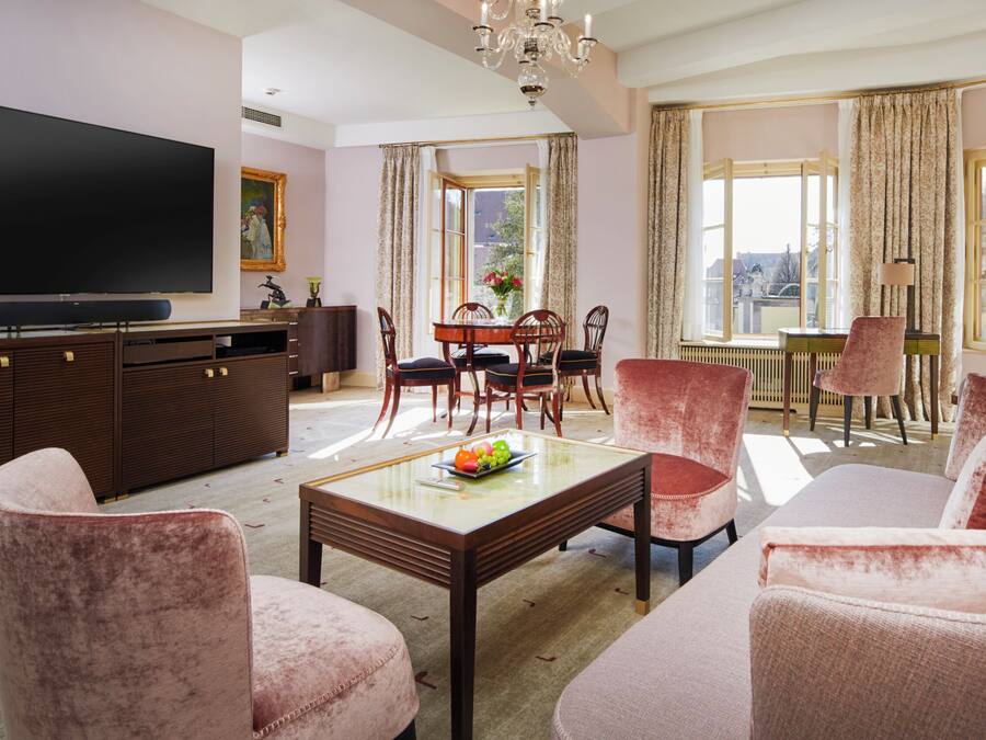 Una sala de estar con sofá, sillas, una mesa de centro, televisor y un comedor con mesa y sillas.