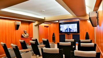 Um cinema em casa com poltronas reclináveis, uma televisão de tela grande e uma estátua na parede.