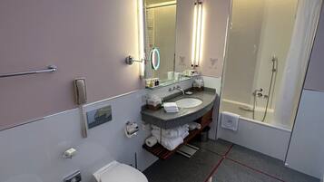 Un baño moderno con tragaluz, un espejo grande, un lavabo, un inodoro y una zona de ducha.