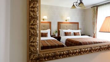 A hotel room with two beds, a large mirror, and a chandelier.