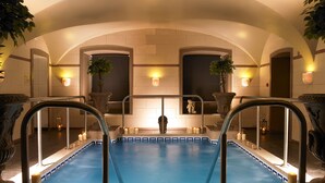 Piscina com borda azulejada, grades de metal e luzes fixadas na parede.