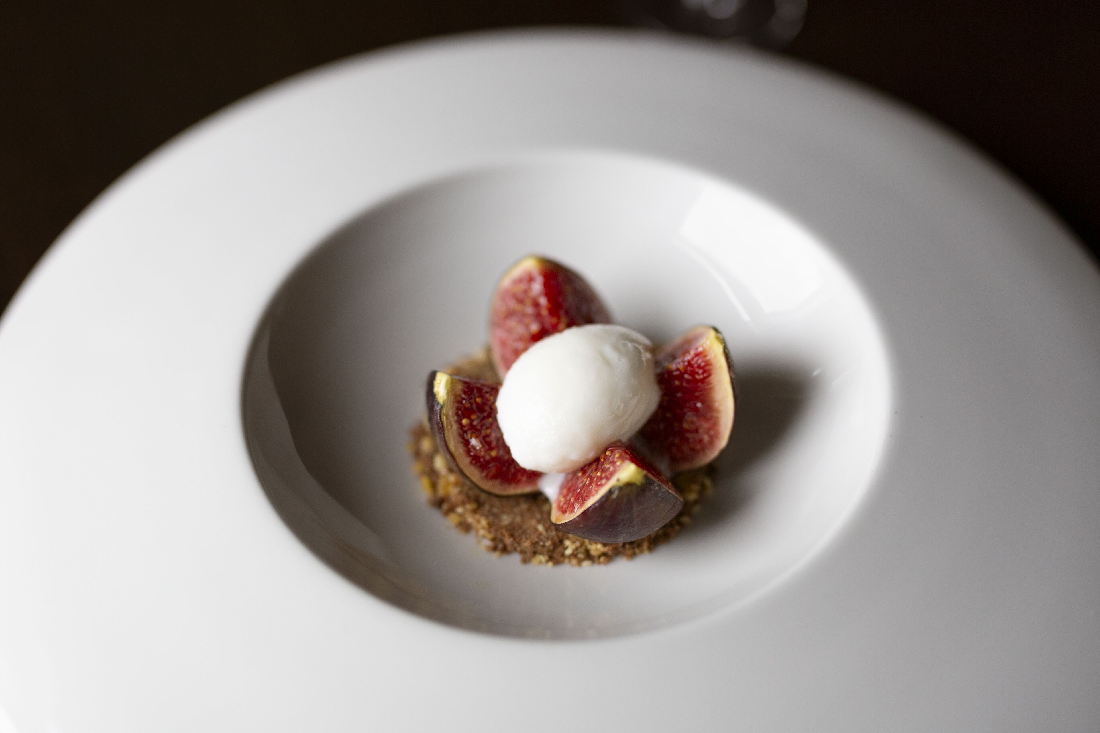 A dessert with a scoop of ice cream and figs on a plate.