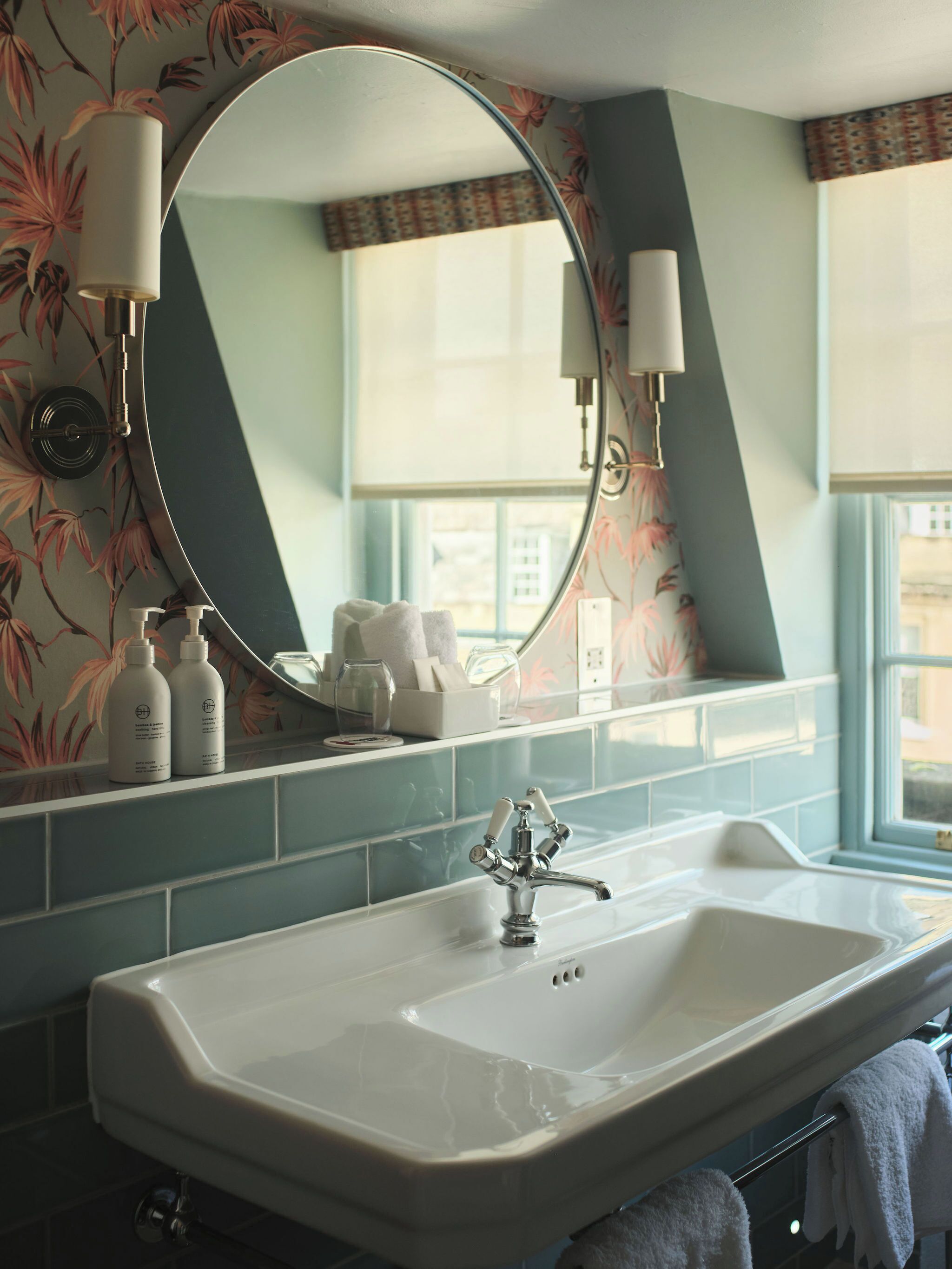 A bathroom with a large mirror, a sink, and toiletries on the counter.