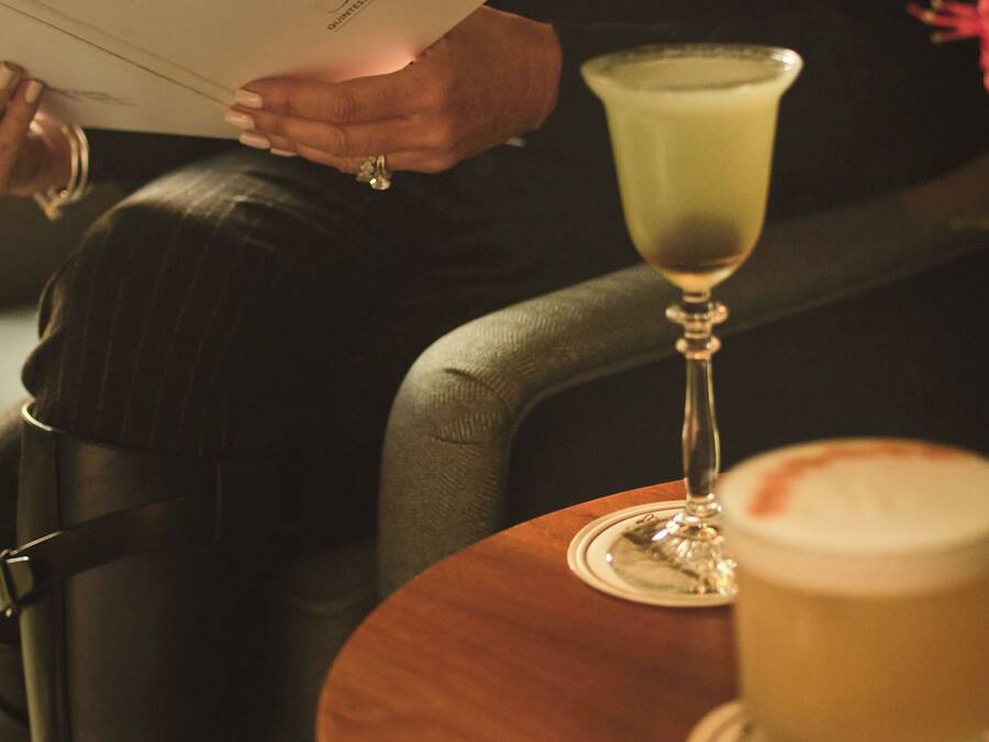 A person holding a menu at a table with a drink and a dessert.