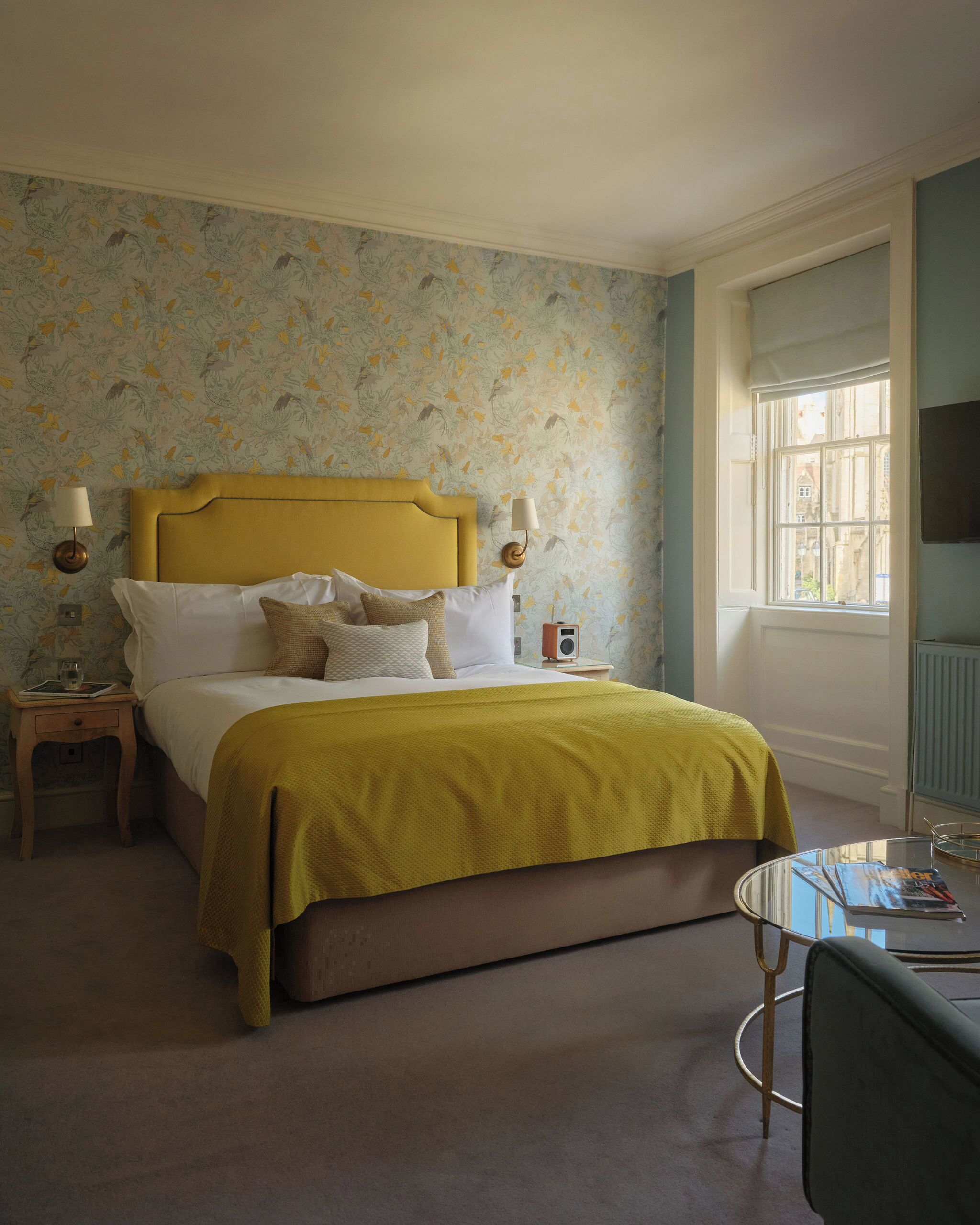 A bedroom with a bed, bedside tables, a lamp, a radio, a window, and a chair.