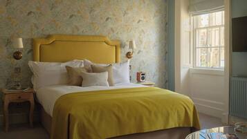 A bedroom with a bed, bedside tables, a lamp, a radio, a window, and a chair.