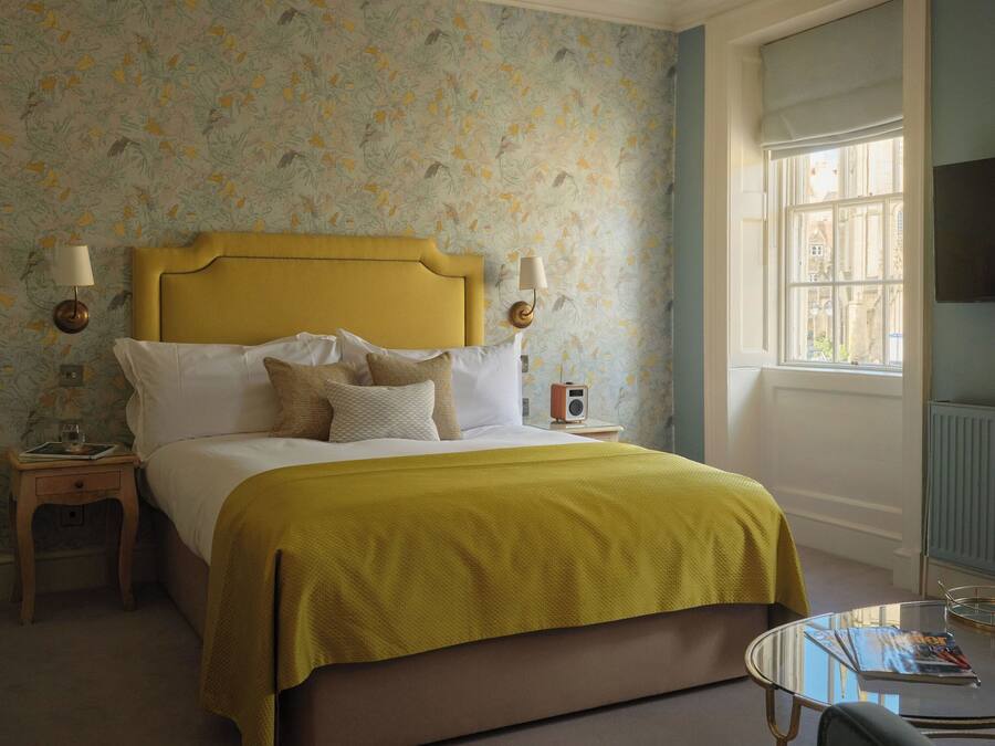 A bedroom with a bed, bedside tables, a lamp, a radio, a window, and a chair.