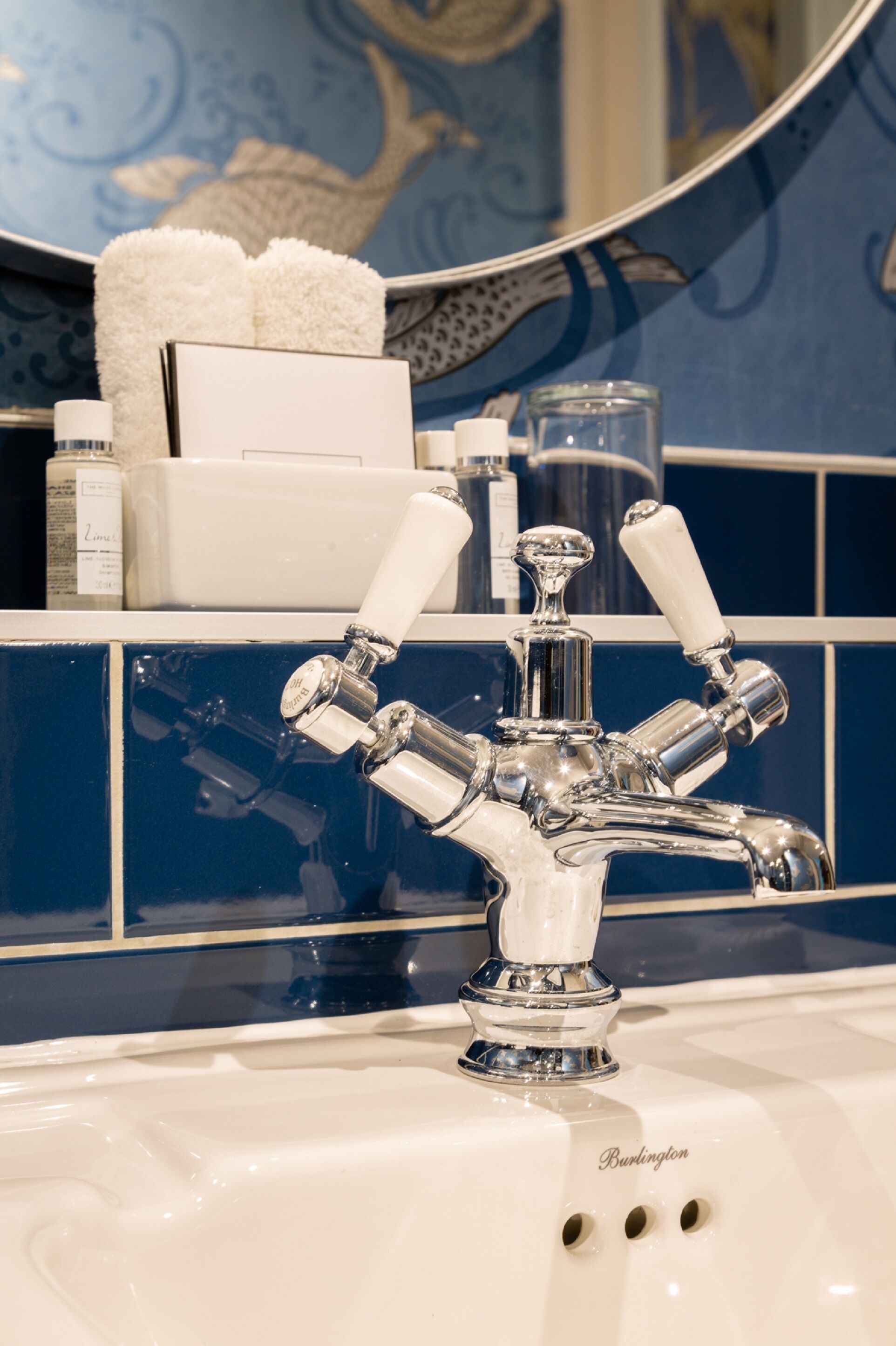 A bathroom with a white sink, a mirror, and a blue tiled wall.