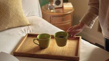 Una bandeja de madera con dos tazas verdes sobre una cama.