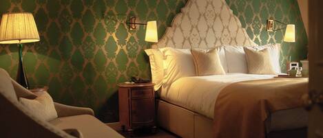 A hotel room with a large bed, two bedside lamps, a nightstand, and a chair.