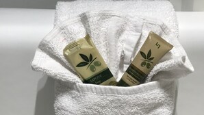 A white towel with two bottles of shampoo and soap in a bathroom setting. - California Inn and Suites Bakersfield (Bakersfield)