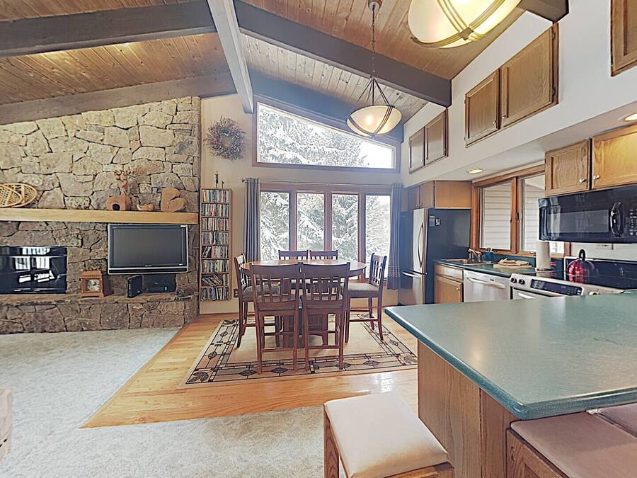 Une cuisine spacieuse avec des meubles en bois, un grand îlot central et une cheminée en pierre.