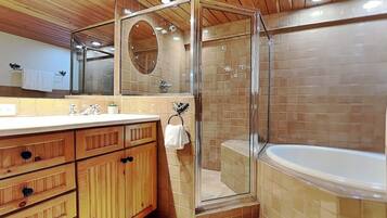 A modern bathroom with a glass-enclosed shower, a large bathtub, wooden cabinets, and a mirror.