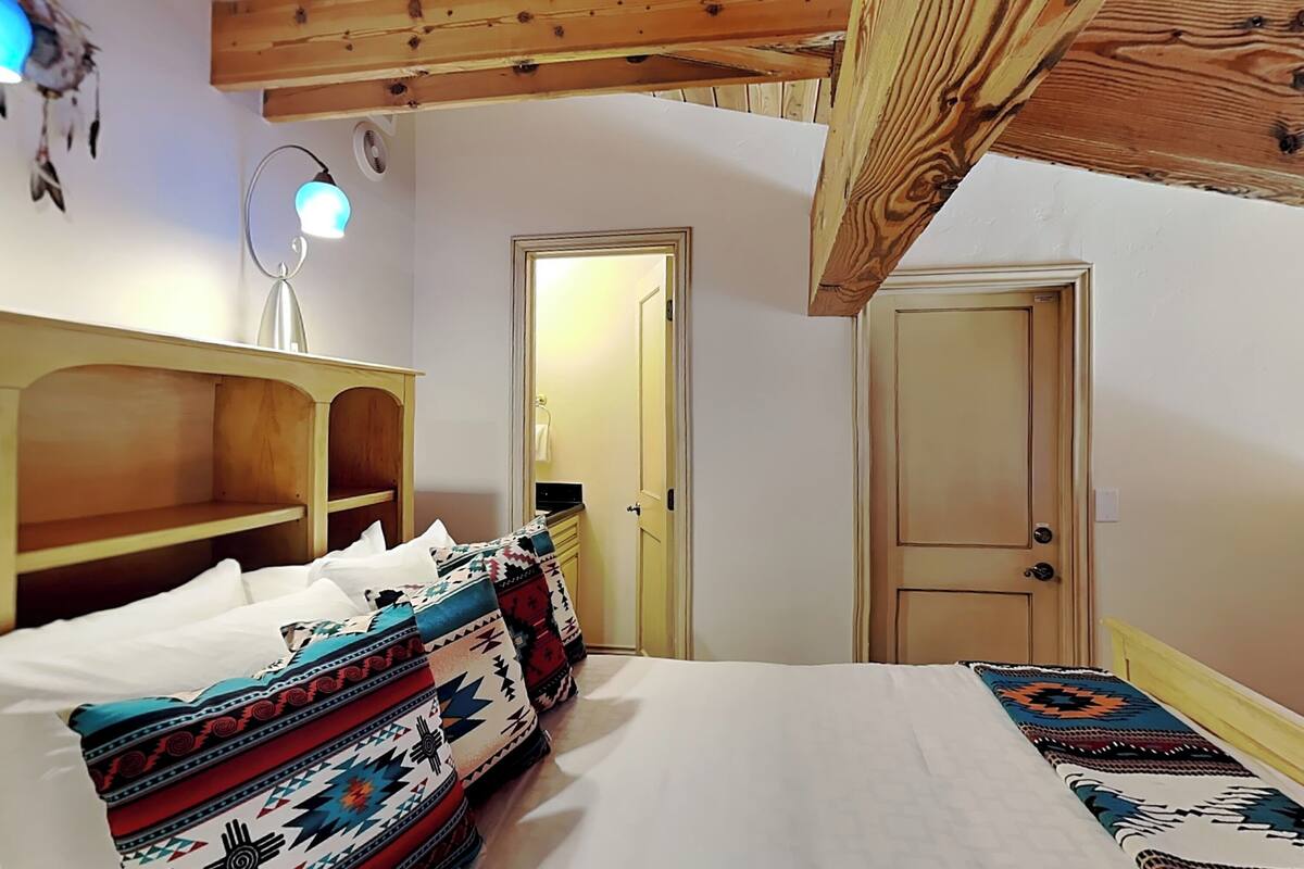 Une pièce comprenant un lit, une étagère en bois, une porte et un luminaire.