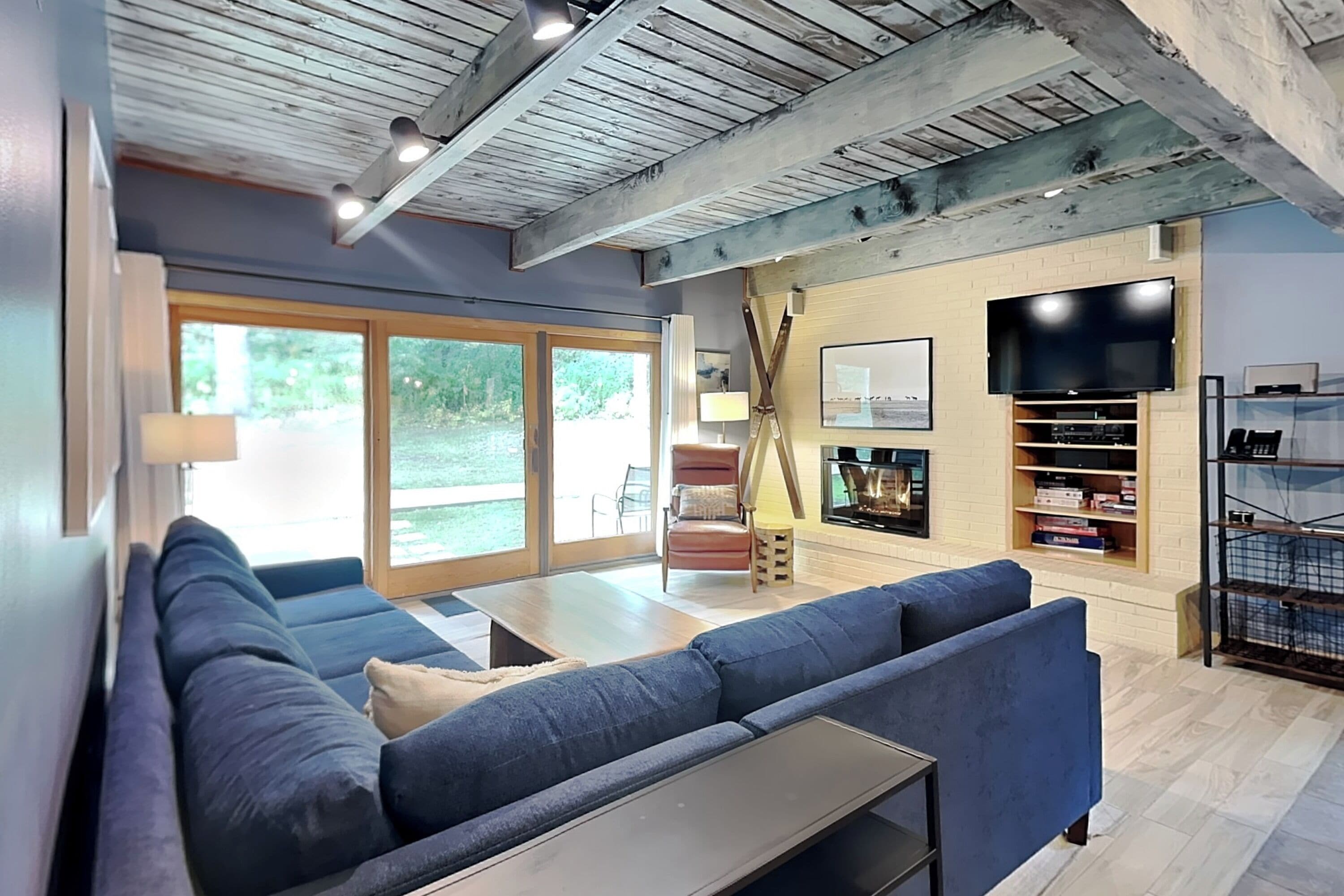 Een moderne woonkamer met een grote bank, een open haard, een flatscreen televisie en een boekenkast.