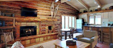 Ein rustikales Cabin-Interieur mit Kamin, Holzwänden, einem Essbereich und einer Küche.