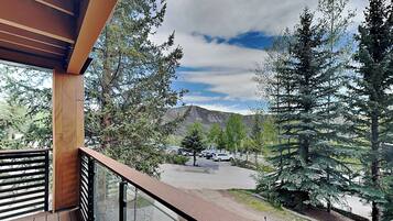 A balcony with a view of a parking area and trees.