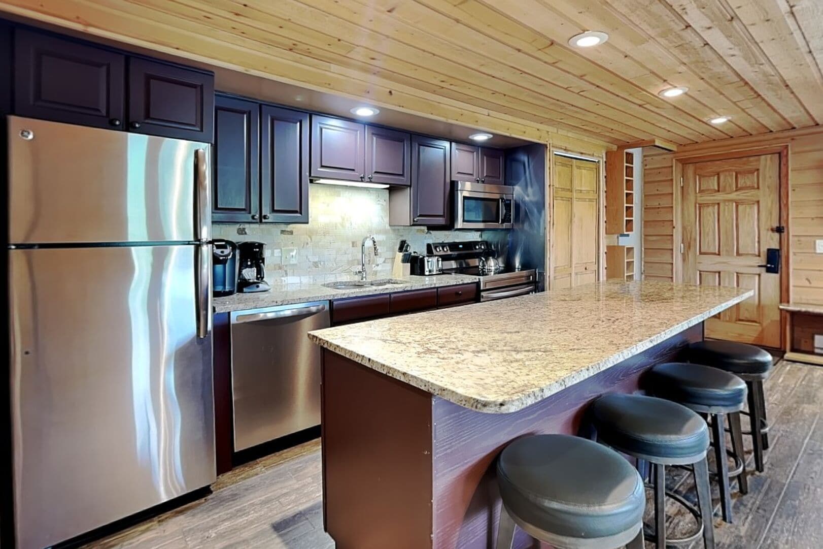 A modern kitchen with stainless steel appliances, dark cabinets, and a granite countertop.
