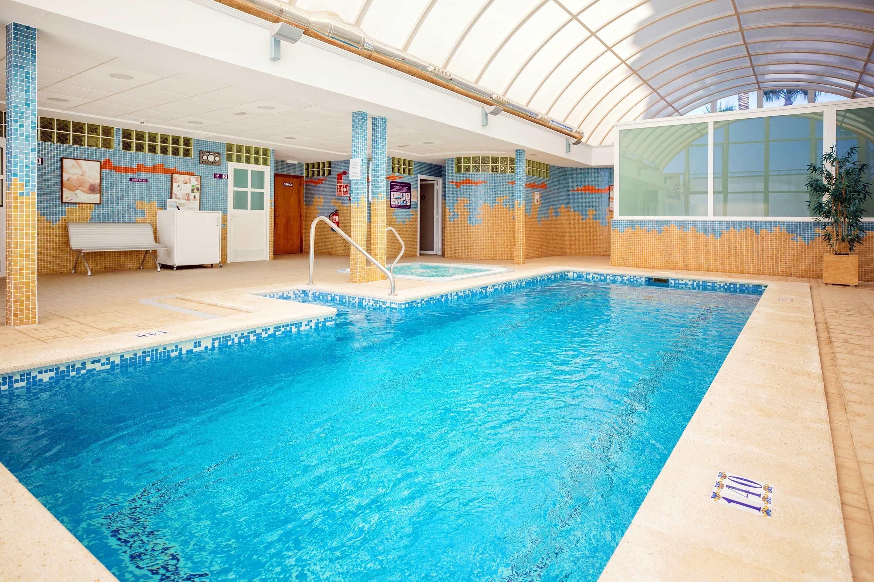An indoor swimming pool with tiled walls, a bench, and a door.