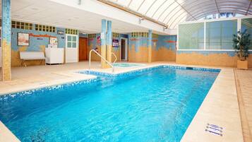 An indoor swimming pool with tiled walls, a bench, and a door.