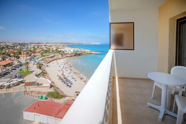 A balcony with a view of a beach and a distant cityscape. - Hotel Servigroup La Zenia (Orihuela)