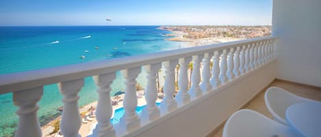 Un balcon avec vue sur la mer et la plage, une balustrade blanche et une petite table.