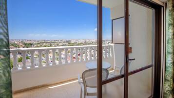 A balcony with a white railing, a white chair, and a table.