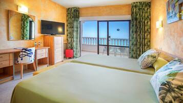 Habitación de hotel con cama, escritorio, televisión y balcón con vistas.