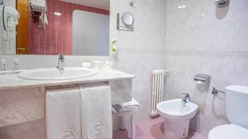 A bathroom with two sinks, a bidet, a toilet, a mirror, and a towel rack.