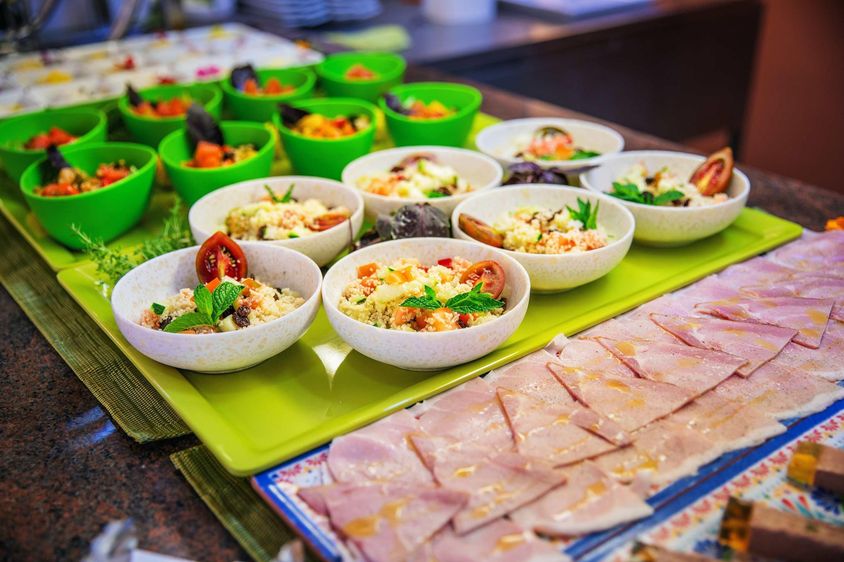 A buffet with various dishes in bowls and a large platter of sliced meat.