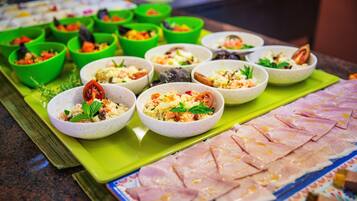 A buffet with various dishes in bowls and a large platter of sliced meat.