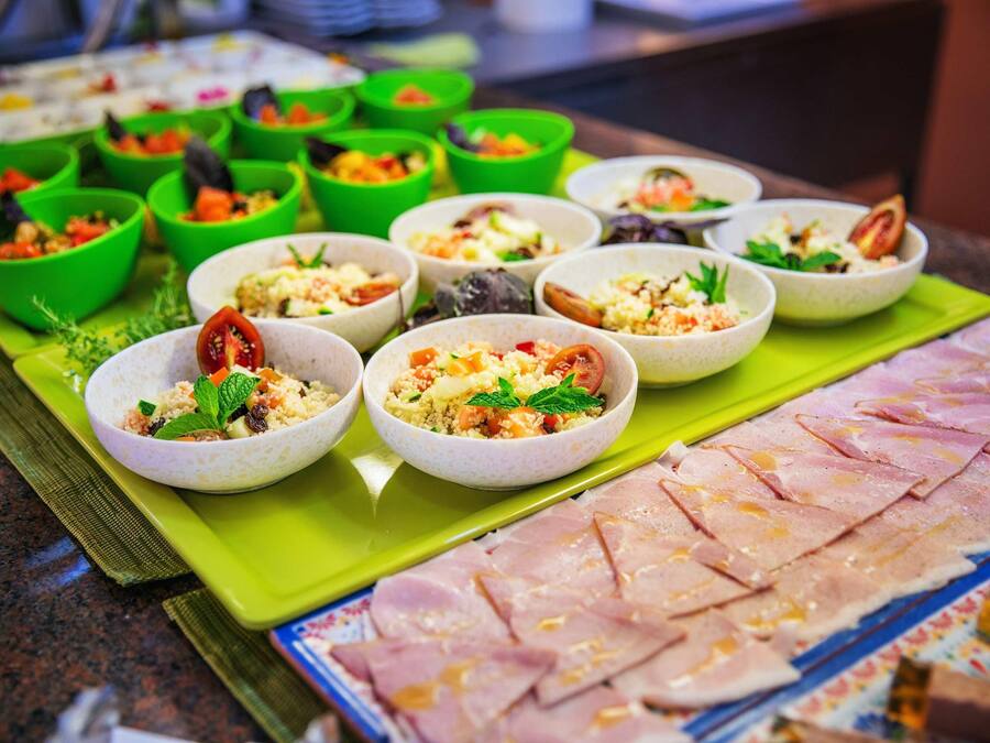A buffet with various dishes in bowls and a large platter of sliced meat.