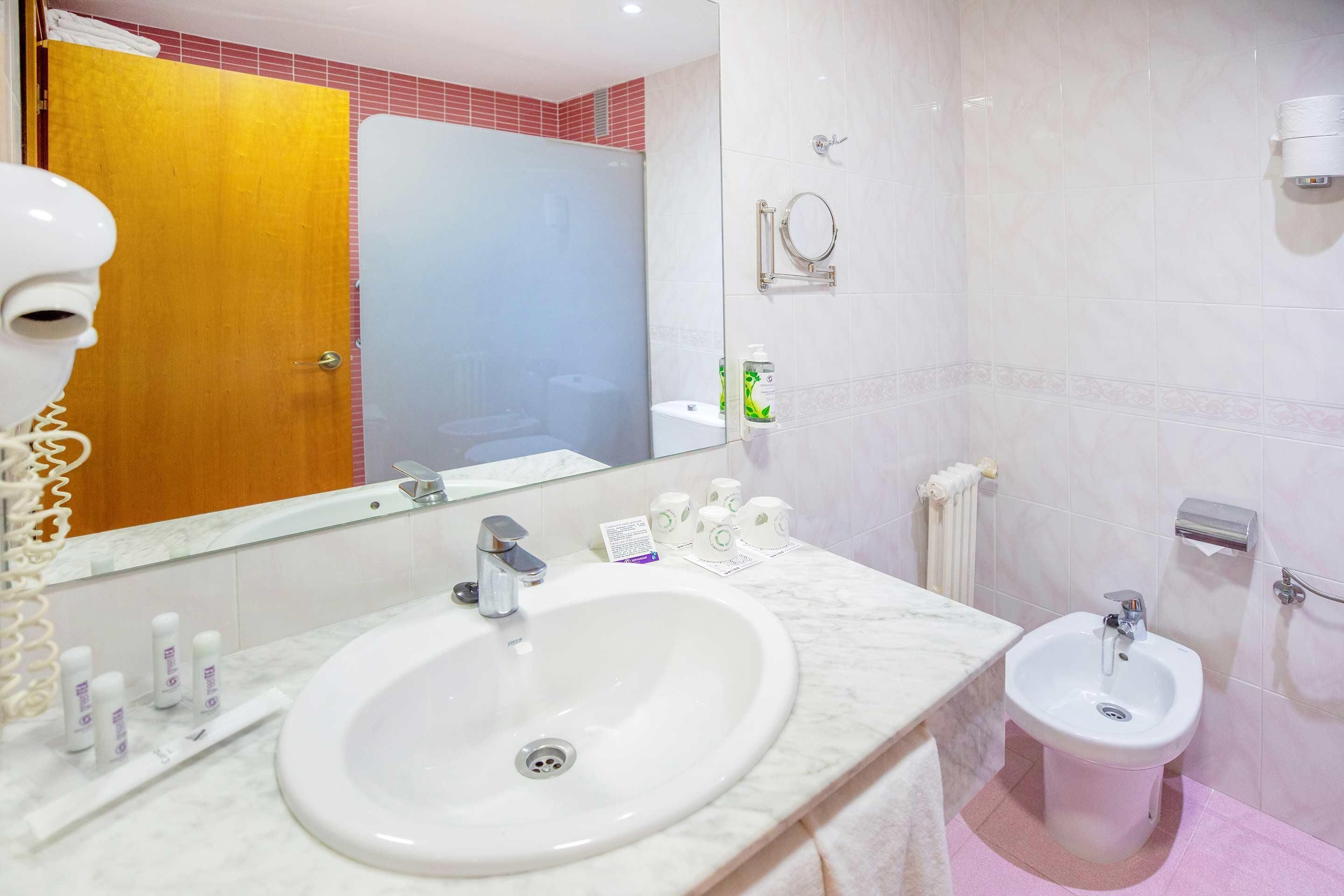 Un bagno con lavabo in marmo, un bidet, uno specchio e un porta asciugamani.
