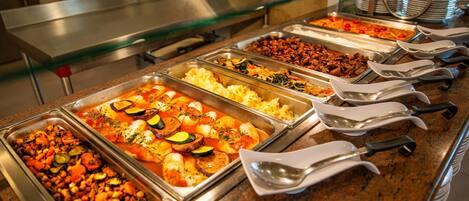 A buffet with various dishes including pasta, meats, and vegetables.