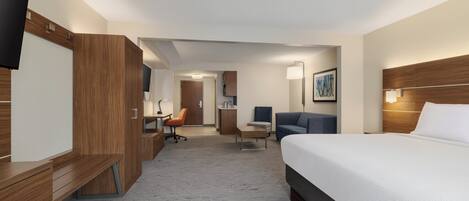 Una habitación de hotel con cama, escritorio, silla y televisor.