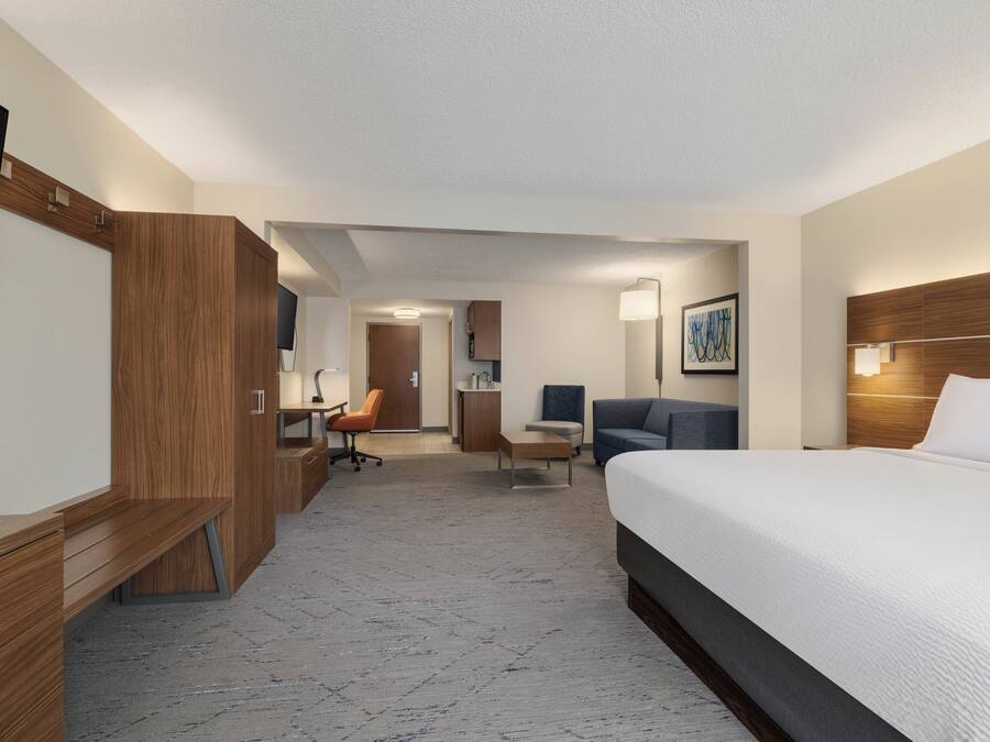 A hotel room with a bed, desk, chair, and a television.