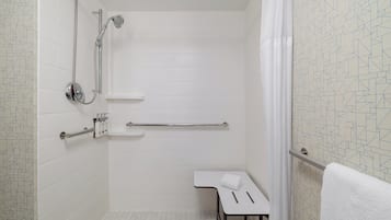 Un baño con ducha, inodoro, toallero y una mesita.