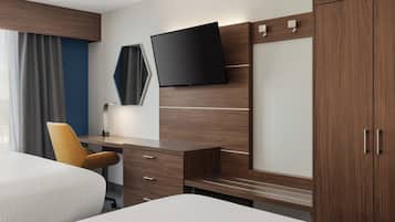 A hotel room with a bed, a desk, a chair, a TV, and a wardrobe.
