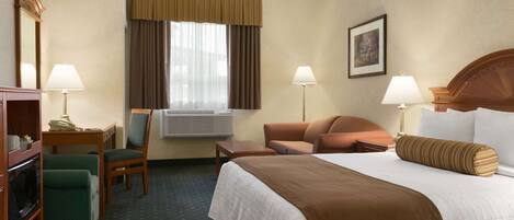 Habitación de hotel con una cama grande, dos sillas, un escritorio y una ventana con cortinas.