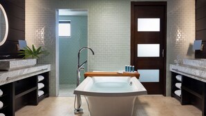 A modern bathroom with a freestanding bathtub, two sinks with marble countertops, and a large mirror above each sink.