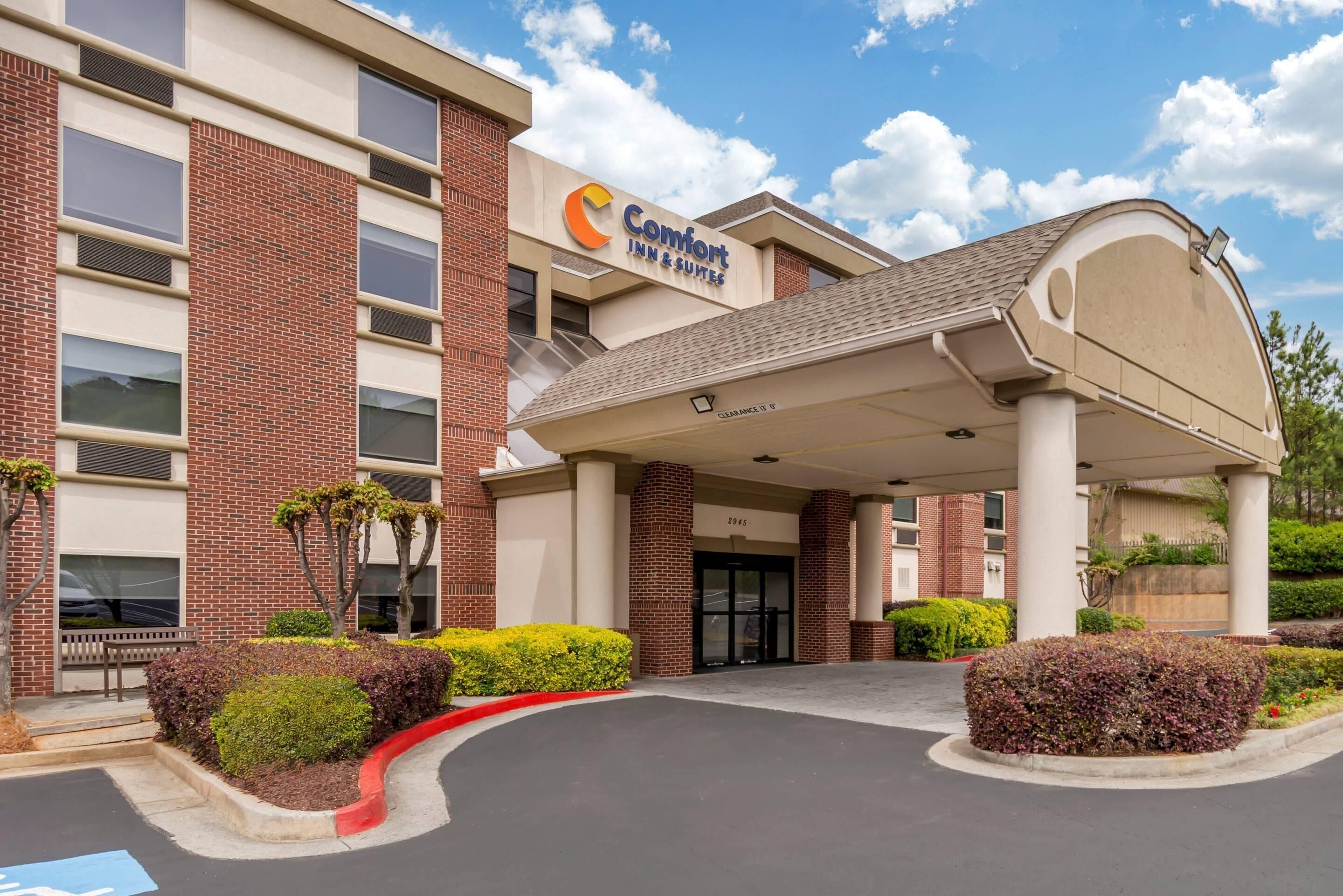 Un hôtel Comfort Inn & Suites avec une façade en briques, une entrée abritée et un parking.