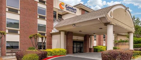 Un hôtel Comfort Inn & Suites avec une façade en briques, une entrée abritée et un parking.
