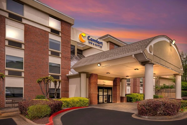 Un hotel Comfort Inn & Suites con fachada de ladrillo, un acceso cubierto y un cielo despejado.