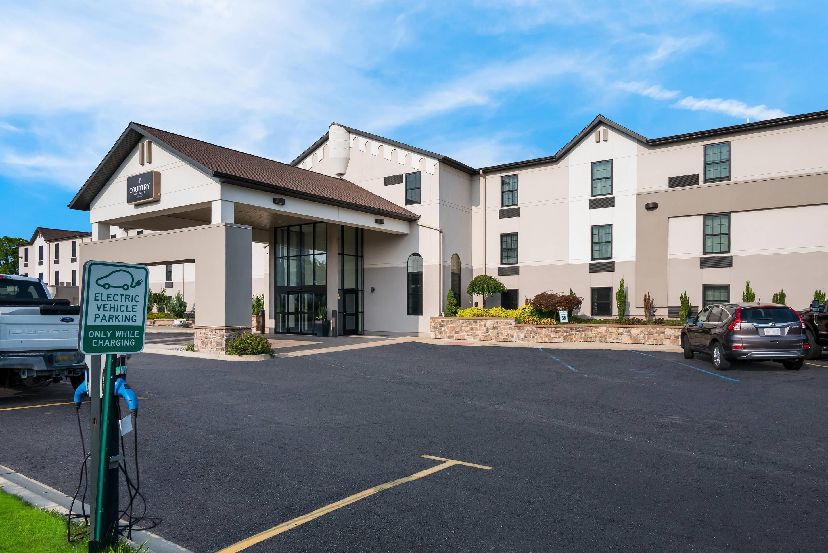 Ein Hotel mit modernem Design, einer Ladestation für Elektrofahrzeuge und einem Parkplatz.