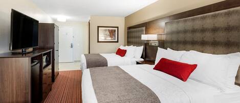 Habitación de hotel con dos camas, televisión, escritorio y puerta.