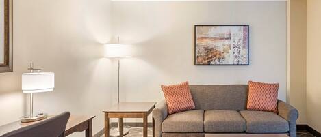 A modern living room with a sofa, a coffee table, a desk, and a lamp.