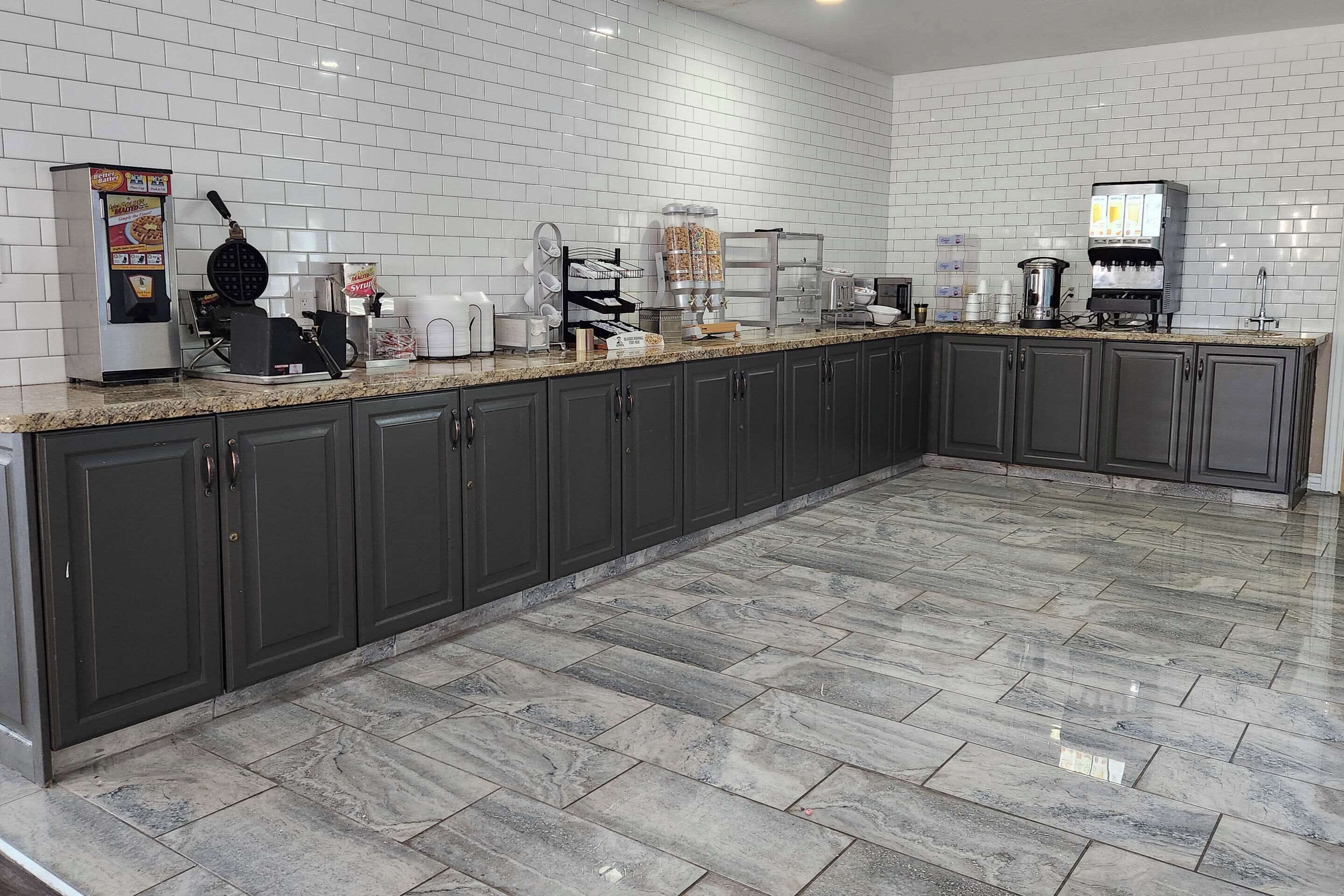 A modern kitchen with dark cabinets, a granite countertop, and white tiled backsplash.