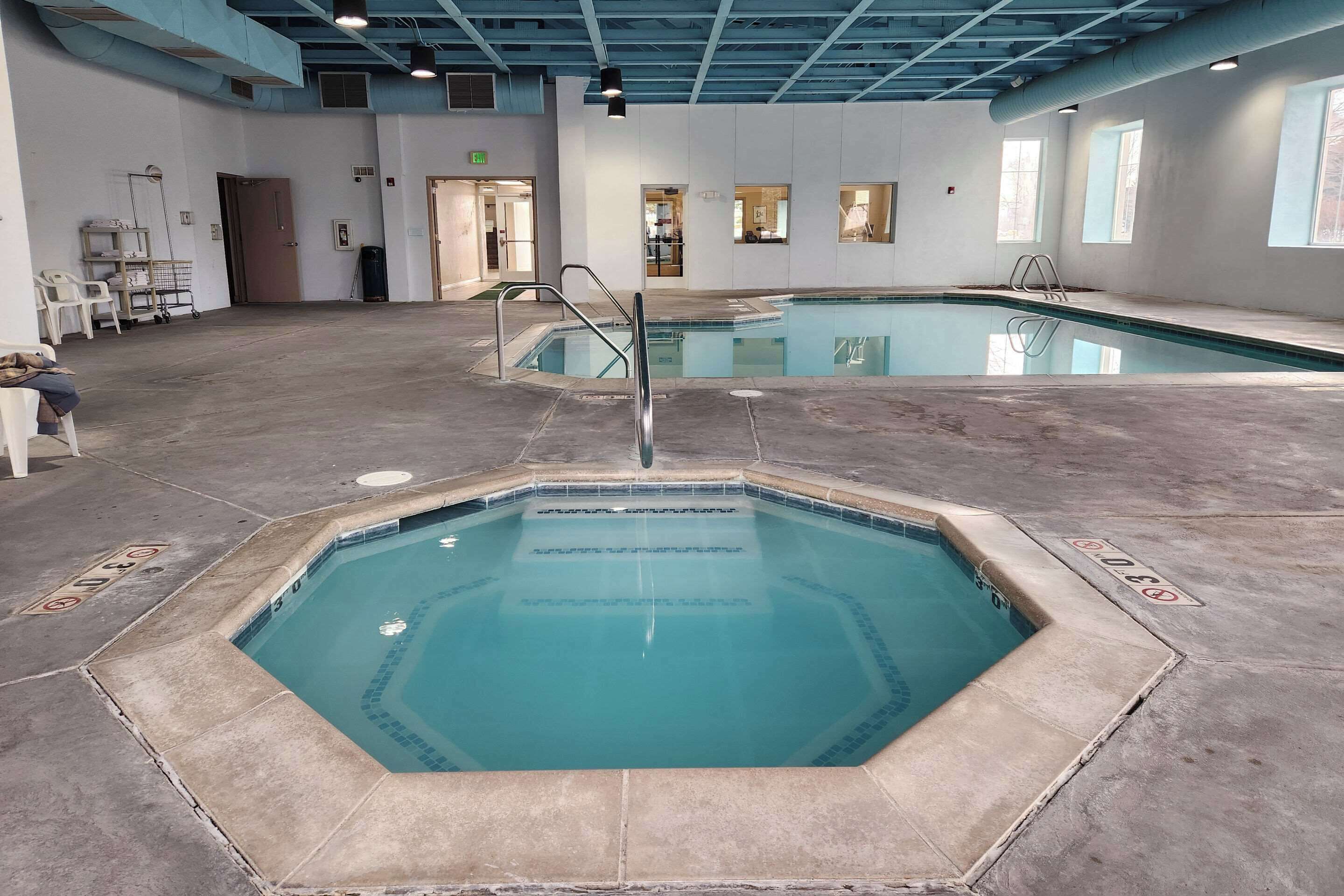 An indoor swimming pool with a clear water surface, surrounded by a tiled deck.